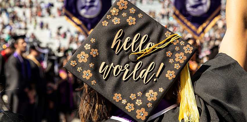 The back of a student's graduation cap which says 'hello world!'