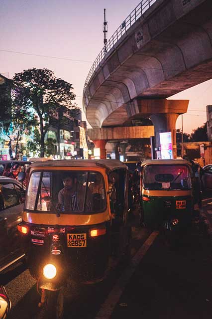 photo of Rickshaws at dusk under the Bangalore metro tracks