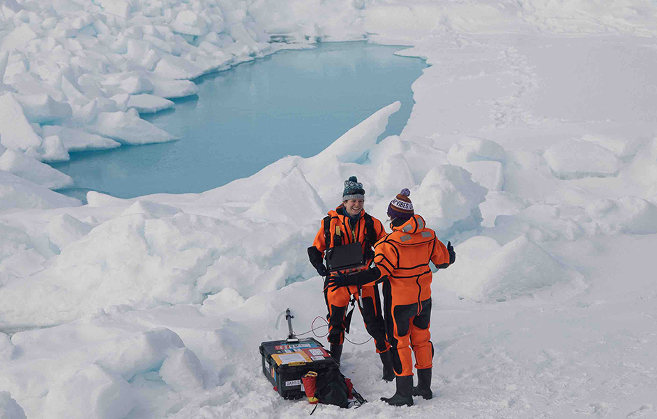 Two researchers standing on sea ice