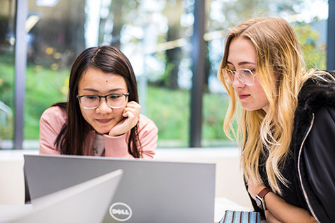 two students looking at a laptop