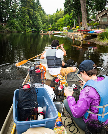 Associate professor Rebecca Neumann and field technician Marco Barajas in a canoe with lots of equipment