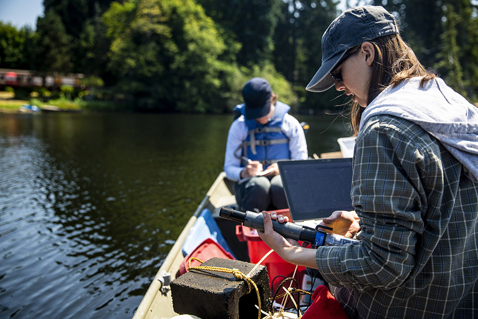 Faculty member and student working in the field; on a small vessel using computer equipment