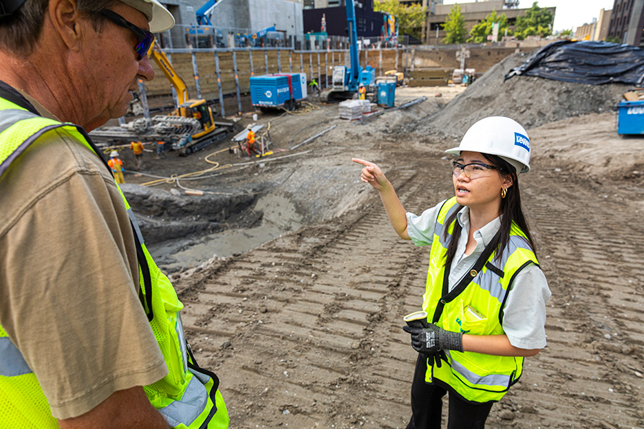 Nancy Le pointing at a construction site to a coworker