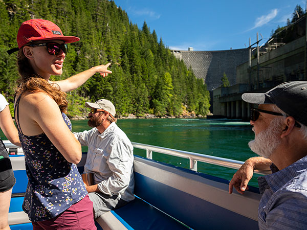 student pointing at a dam from a boat on a river