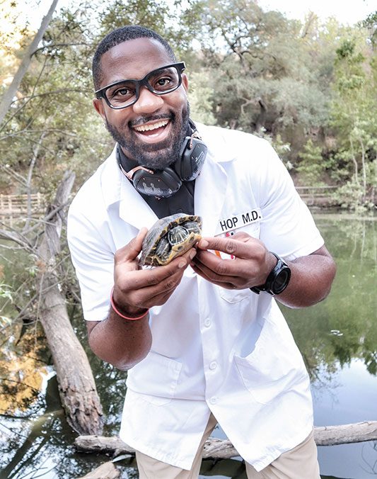 Okereke standing in front of a lake and holding a turtle