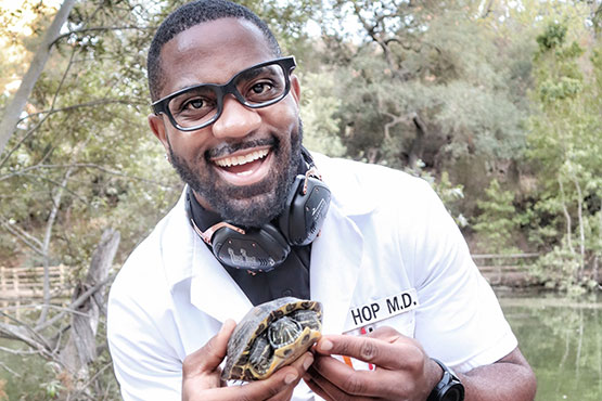 Okereke standing in front of a lake and holding a turtle