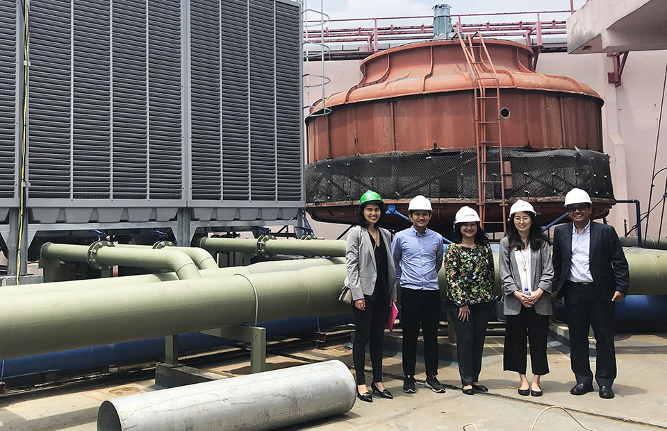 A group of people wearing hard hats standing in front of an old boiler