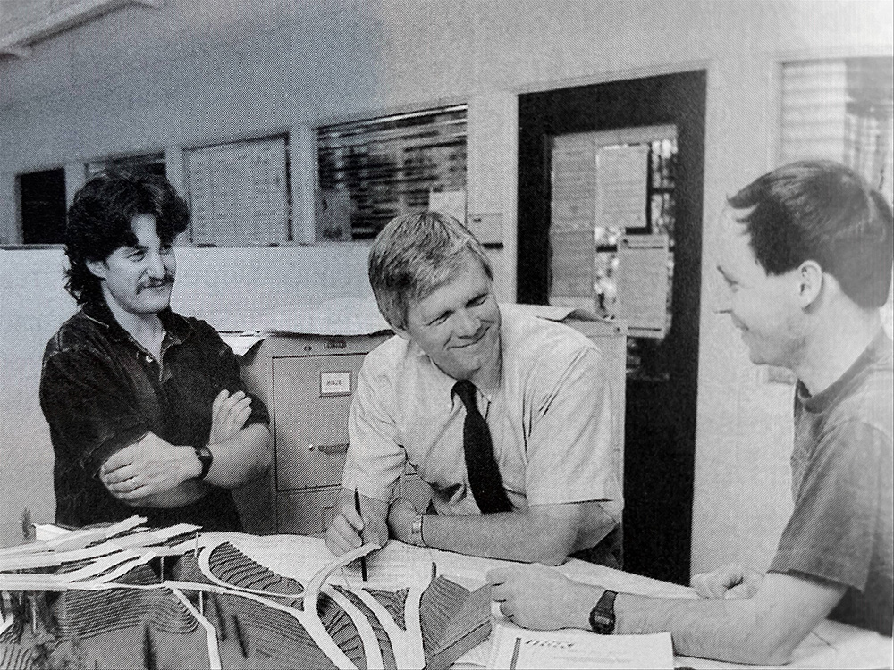 An old black and white photo that shows Joe Mahoney speaking with two colleagues