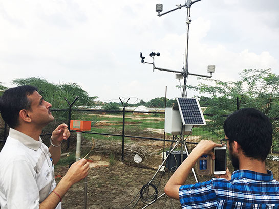 Two researchers setting up a weather station