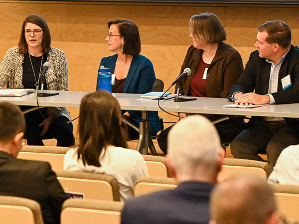 speakers sitting at a long table at a conference