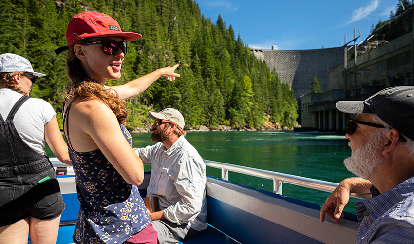 A student pointing at a dam from a boat