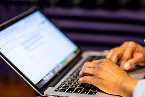 Hands typing on a laptop