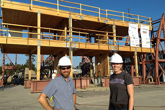 Two researchers standing in front of a timber structure