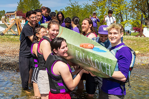 A group of students carrying a concrete canoe
