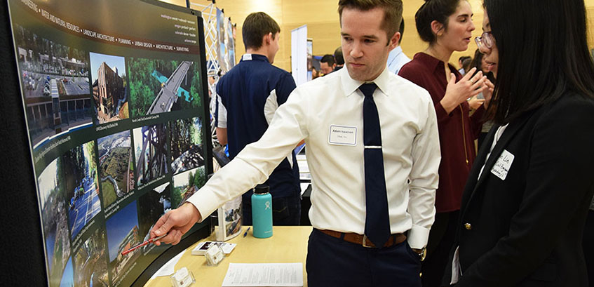 person explaining career fair display to student