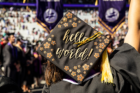 The back of a student's graduation cap which says 'hello world!''