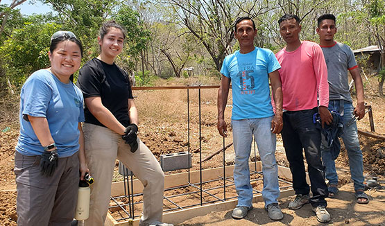 EWB team members Avocet Nagle-Christensen and Monika Kaneshige (left to right) and CAPS members work standing in front of two composting latrines.