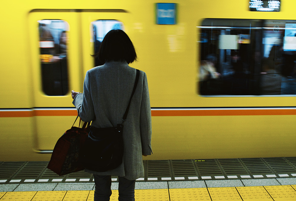 A person with their back to the camera standing in front of a moving train