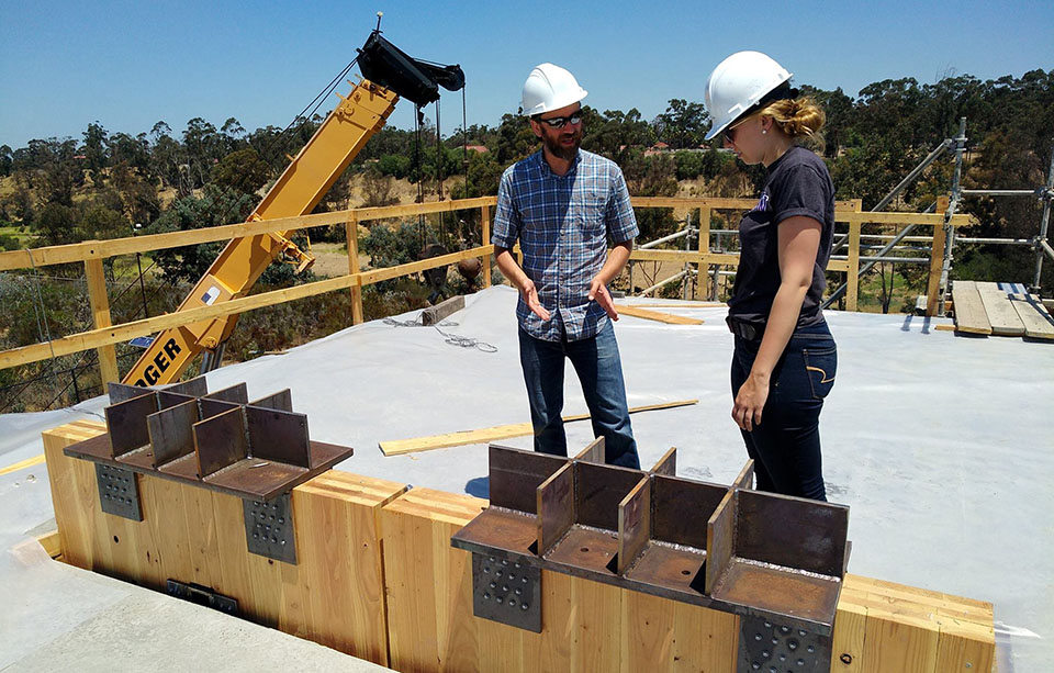 Standing on top of the roof of the two-story structure, associate professor Jeff Berman and graduate student Sarah Wichman discuss the installation process for the walls, the PT bars, and the connections. Photo Credit: Shiling Pei.