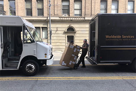 A delivery driver pulling stacks of boxes on a dolly