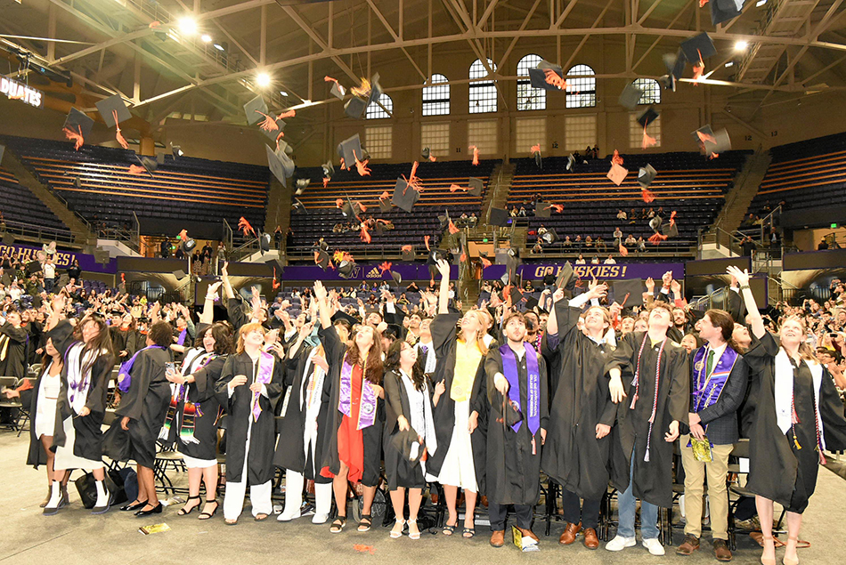 Graduates celebrating by throwing their caps into the air.