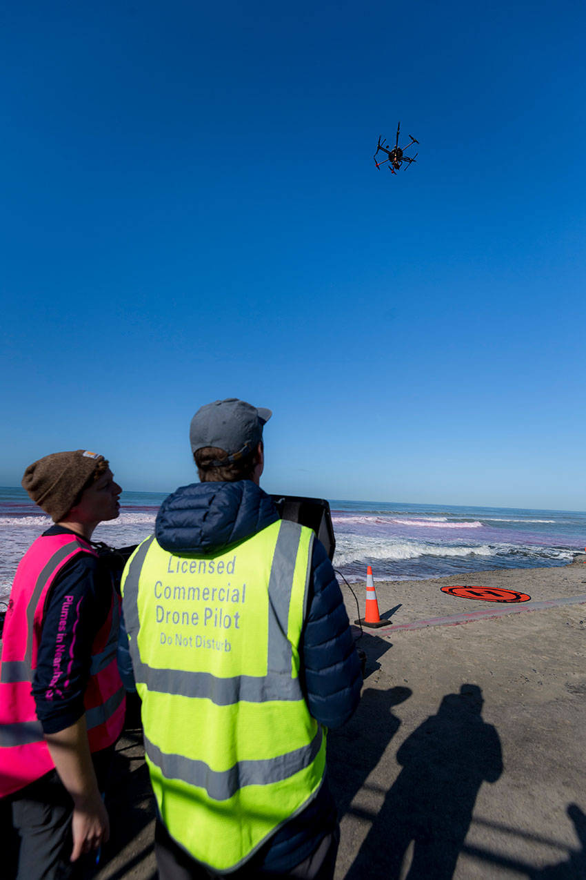 researchers flying a drone on the beach