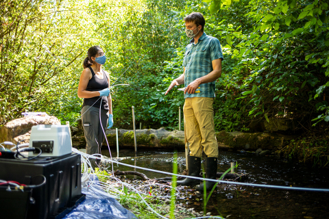 Two researchers standing in a stream while conducting research