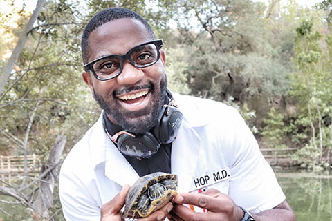 Okereke standing in front of a lake and holding a turtle