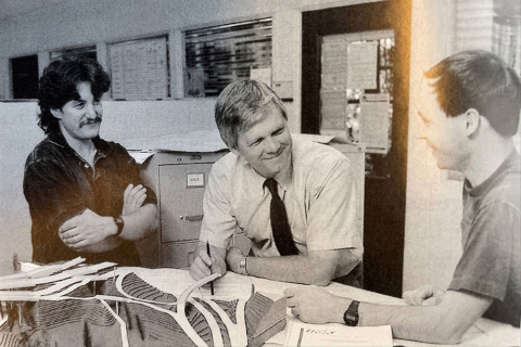 An old black and white photo that shows Joe Mahoney speaking with two colleagues
