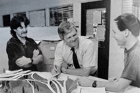 An old black and white photo that shows Joe Mahoney speaking with two colleagues