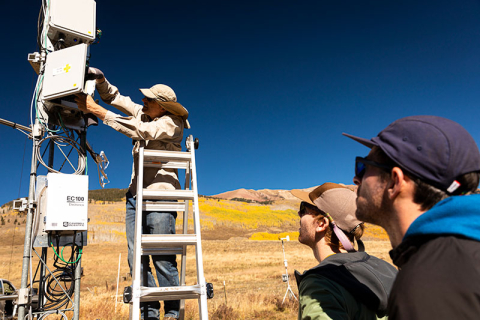 Graduate students Danny Hogan and Eli Schwat look at NCAR engineer Chris Roden while he adjusts some equipment