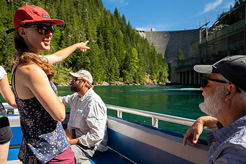 student pointing at a dam from a boat on a river