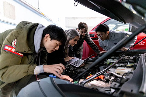 A group of students looking under the hood of an electric car