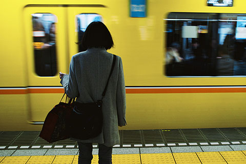 A person with their back to the camera standing in front of a moving train