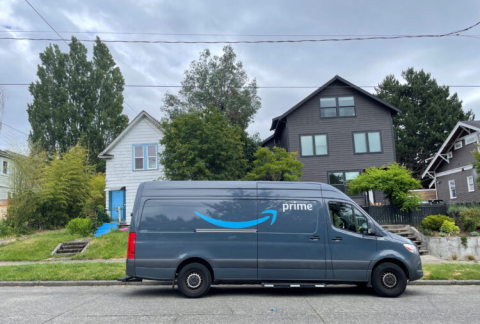 An Amazon van driving in a neighborhood.