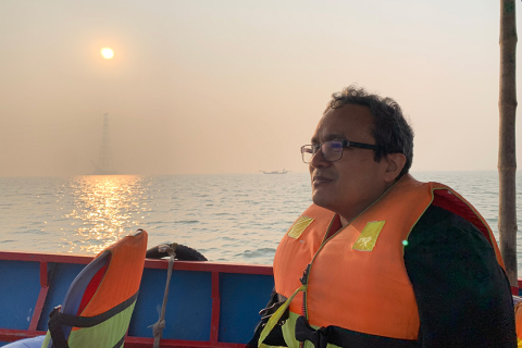 Professor Faisal Hossain on a boat overlooking a Bangladeshi river at sunset