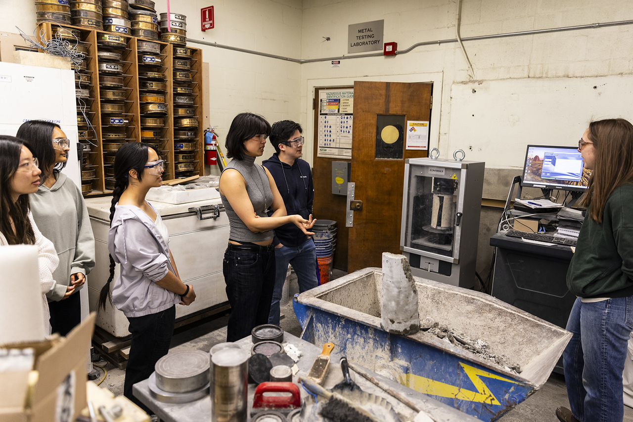 Students in a the construction materials lab observing a demonstration with tools and equipment around