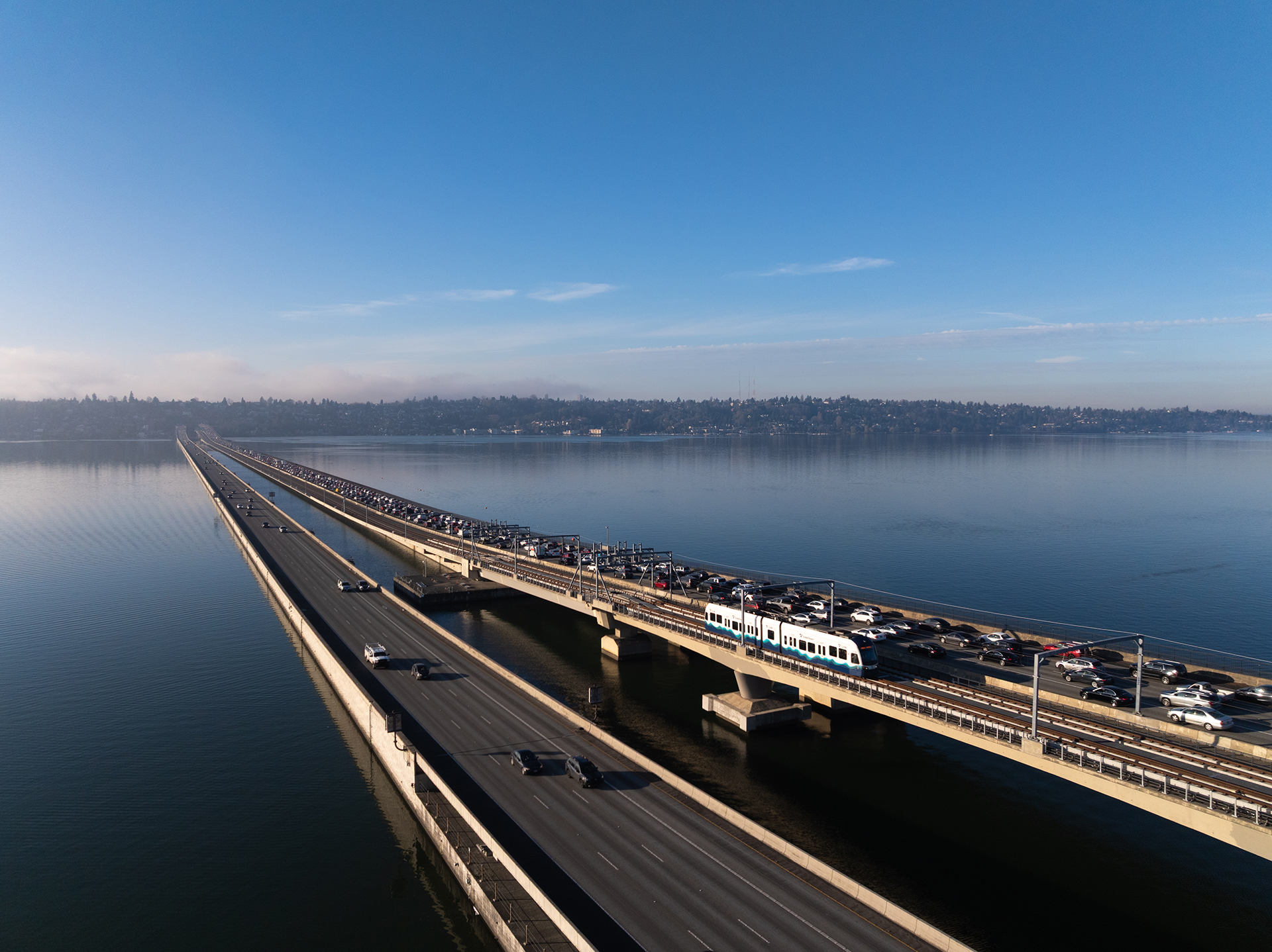 Aerial view of a bridge over water with heavy traffic and a train on the upper level