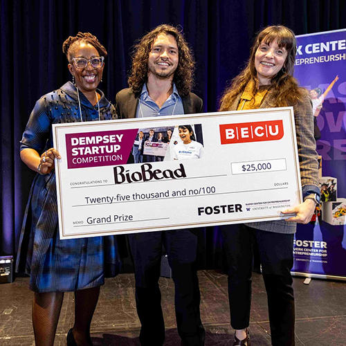 Three BioBead team members holding a large winning check