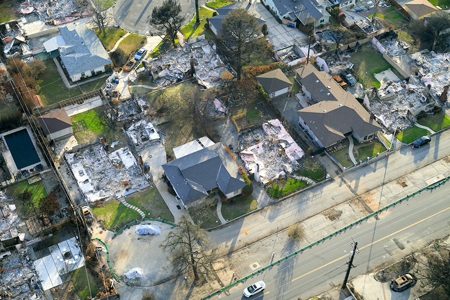 An aerial view of a neighborhood that has some homes completely burned to the ground and some left fully standing.