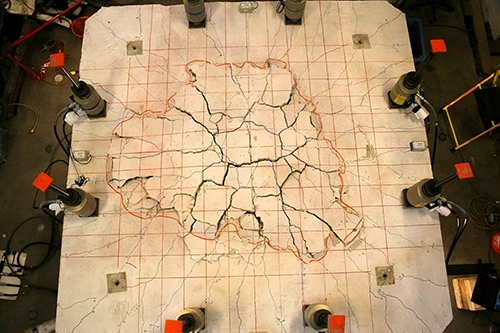 Top view of a slab after a punching shear test, showing cracks radiating outward from the center, where the column supported the slab from below.