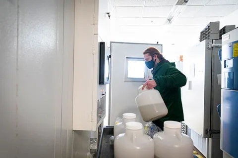 Researcher carrying jugs of wastewater sample for storing in a lab