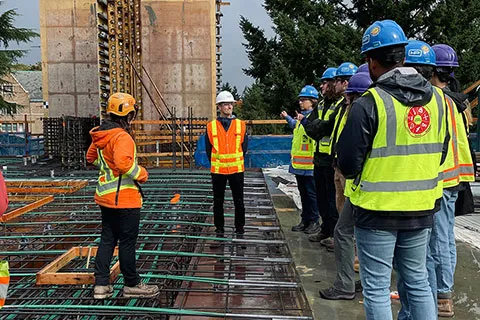 a group of people wearing safety vests and hardhats standing in the IEB construction site