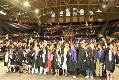 Students throw their graduation caps into the air.