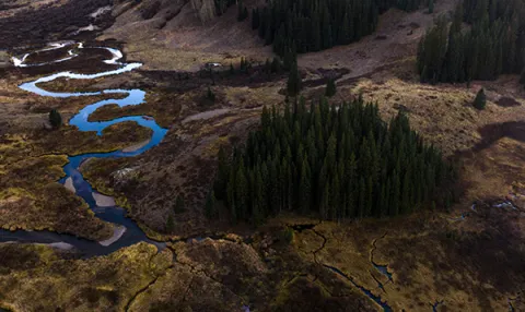 An shot from above of a winding river in a mountain valley.