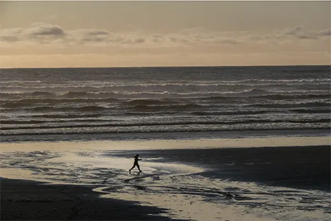 A man walks on a beach with the ocean in the background. . (Dean Rutz / The Seattle Times)