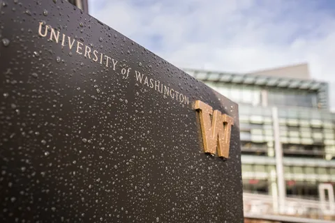 A University of Washington metal sign covered in water droplets.