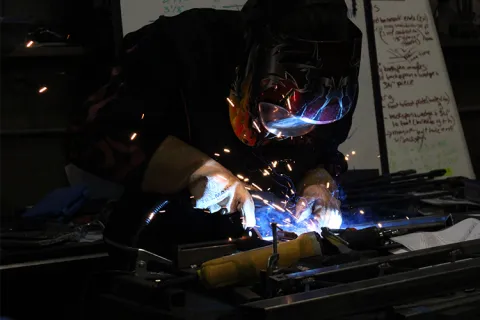 A person welding metal in a workshop