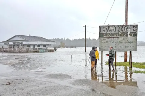 Three people stand in floodwaters