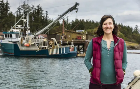 Molly Grear stands on the dock in front of Friday Harbor Labs. The marine research vessel R/V Centennial is in the background.